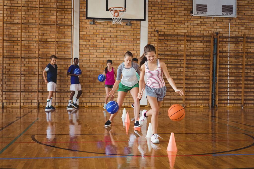 High school kids practicing football using cones for dribbling drill in the court